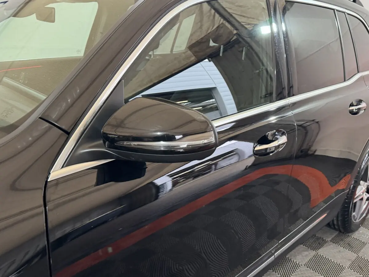 Vue latérale côté gauche sur la porte avant et rétroviseur d’un Mercedes GLB 200 d AMG Line noir brillant.