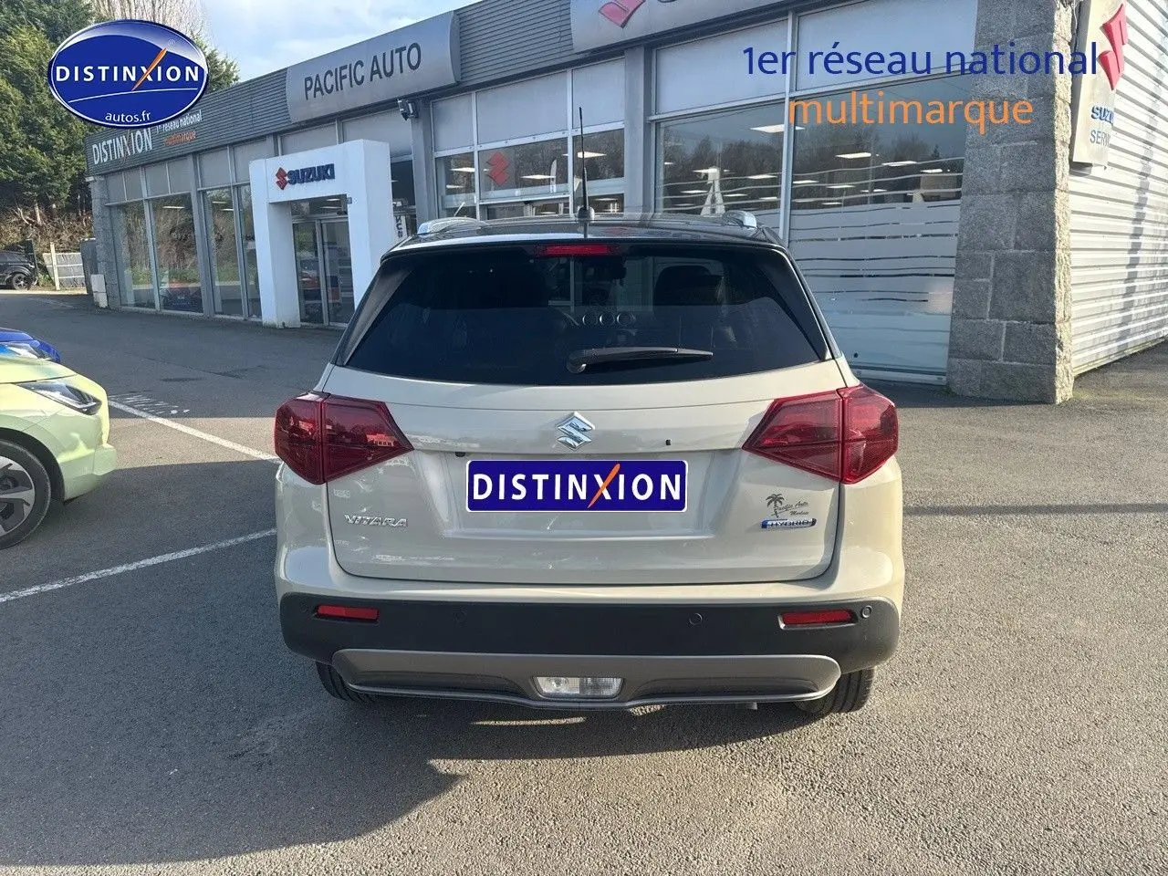 Vue arrière d'un Suzuki Vitara 1.4 Boosterjet Hybrid 2026 en So'Color Savanna Ivory/Black métal, avec feux arrière LED et barres de toit visibles.