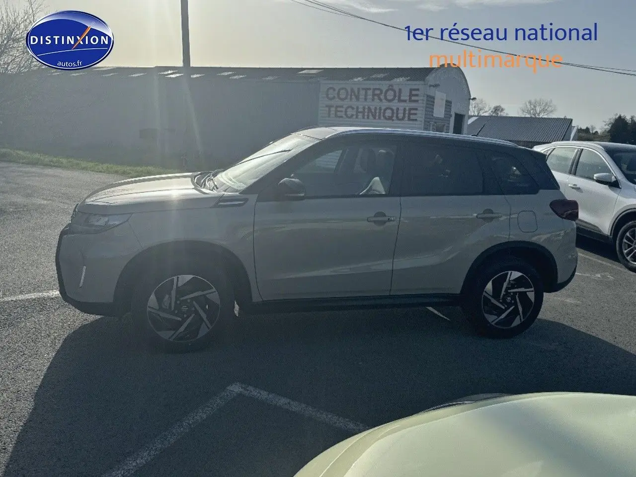 Suzuki Vitara 1.4 Boosterjet Hybrid 2026 vue de profil côté gauche, couleur ivoire et toit noir, jantes alu distinctives.