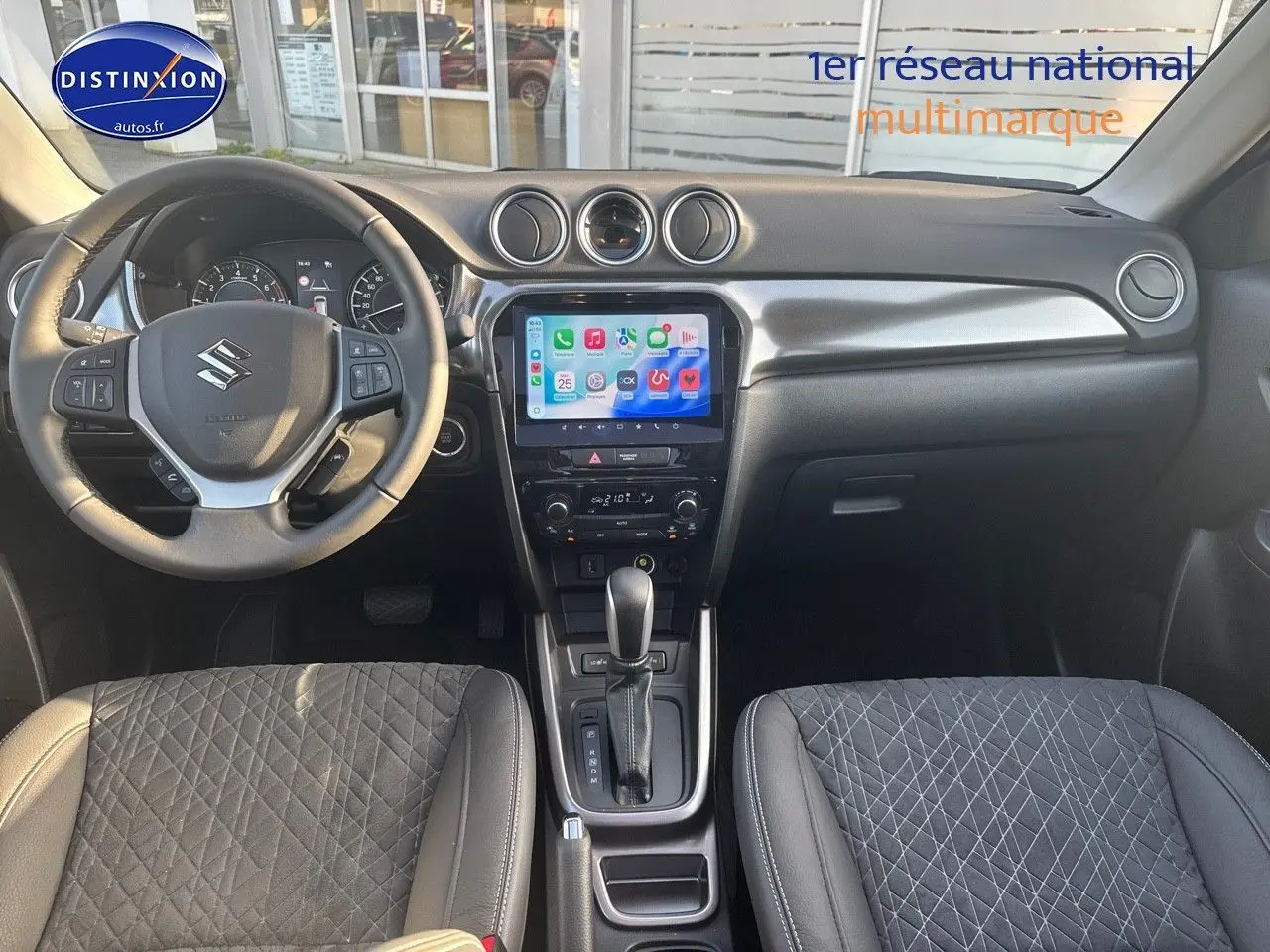 Vue intérieure avant du Suzuki Vitara 1.4 Boosterjet Hybrid 2026, volant multifonction, écran tactile et sièges en suédine noire.