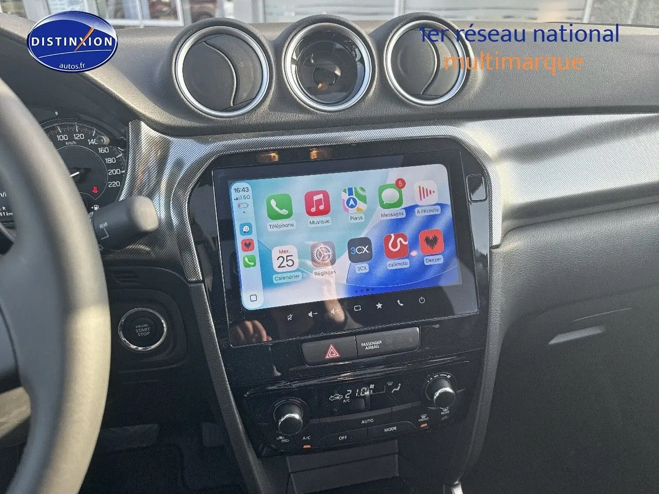 Vue intérieure centrée sur la console centrale noire du Suzuki Vitara avec écran tactile et commandes climatisation visibles.