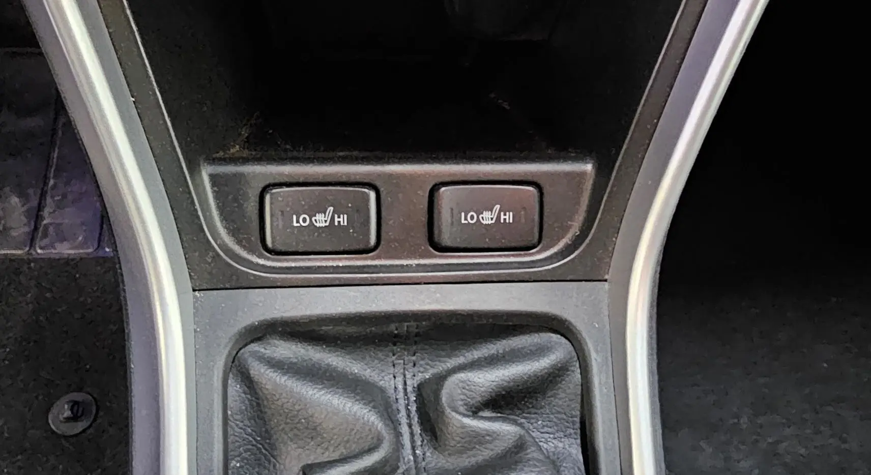 Gros plan sur les boutons de chauffage des sièges et le soufflet de levier de vitesse d'une Suzuki SX4 S-Cross gris 2020.