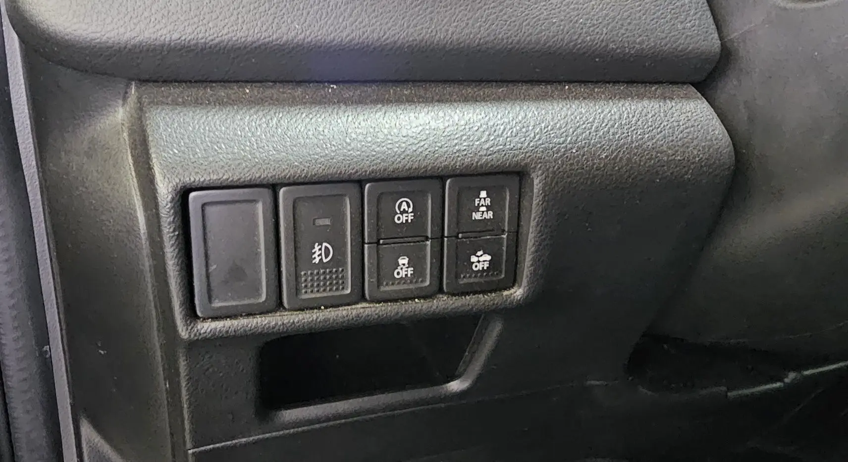 Gros plan sur les commandes de fonctions électroniques à gauche du volant du Suzuki SX4 S-Cross gris 2020.