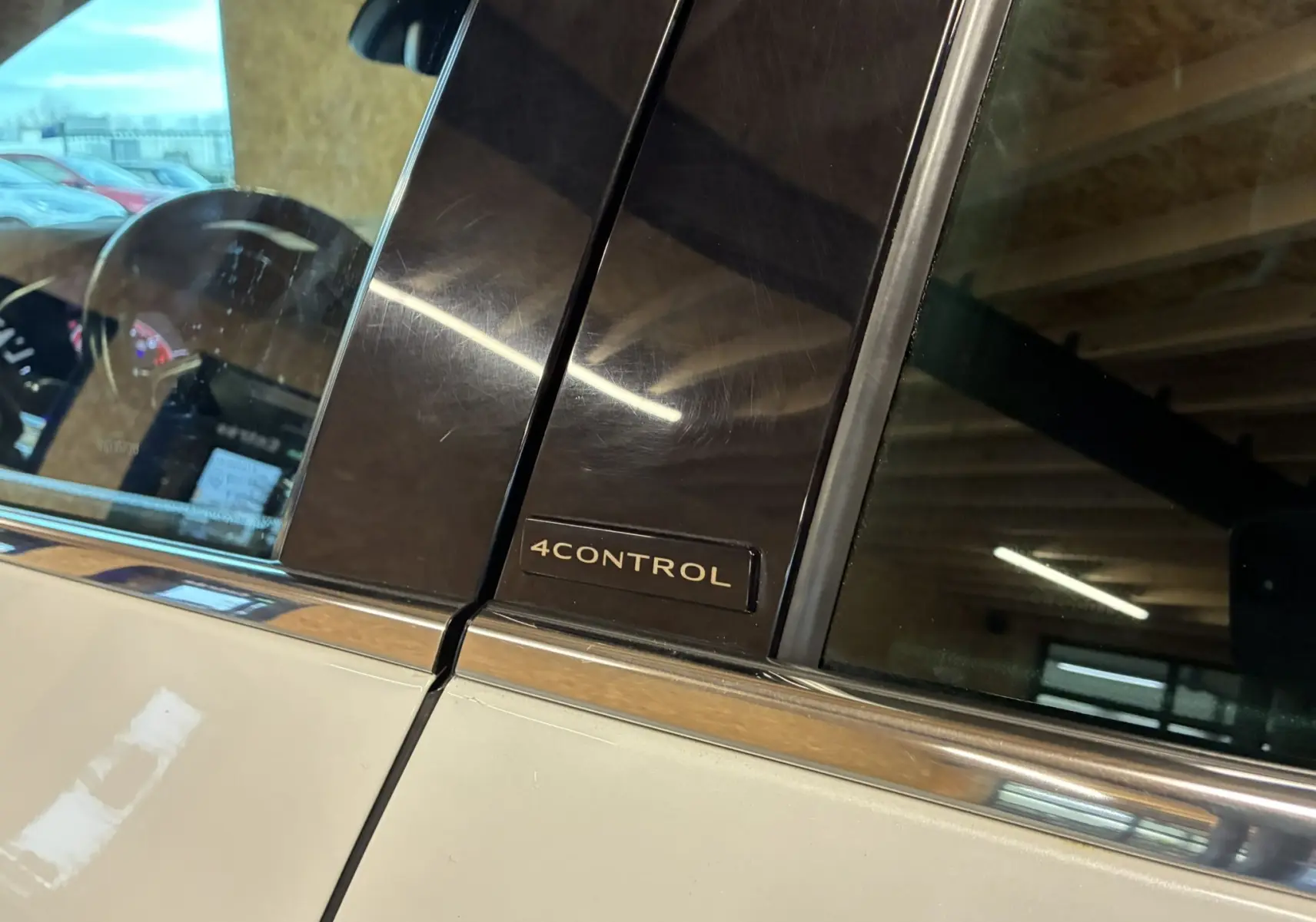 Gros plan sur l’inscription 4CONTROL sur la partie noire entre les vitres avant et arrière d’une Renault Mégane IV blanche.