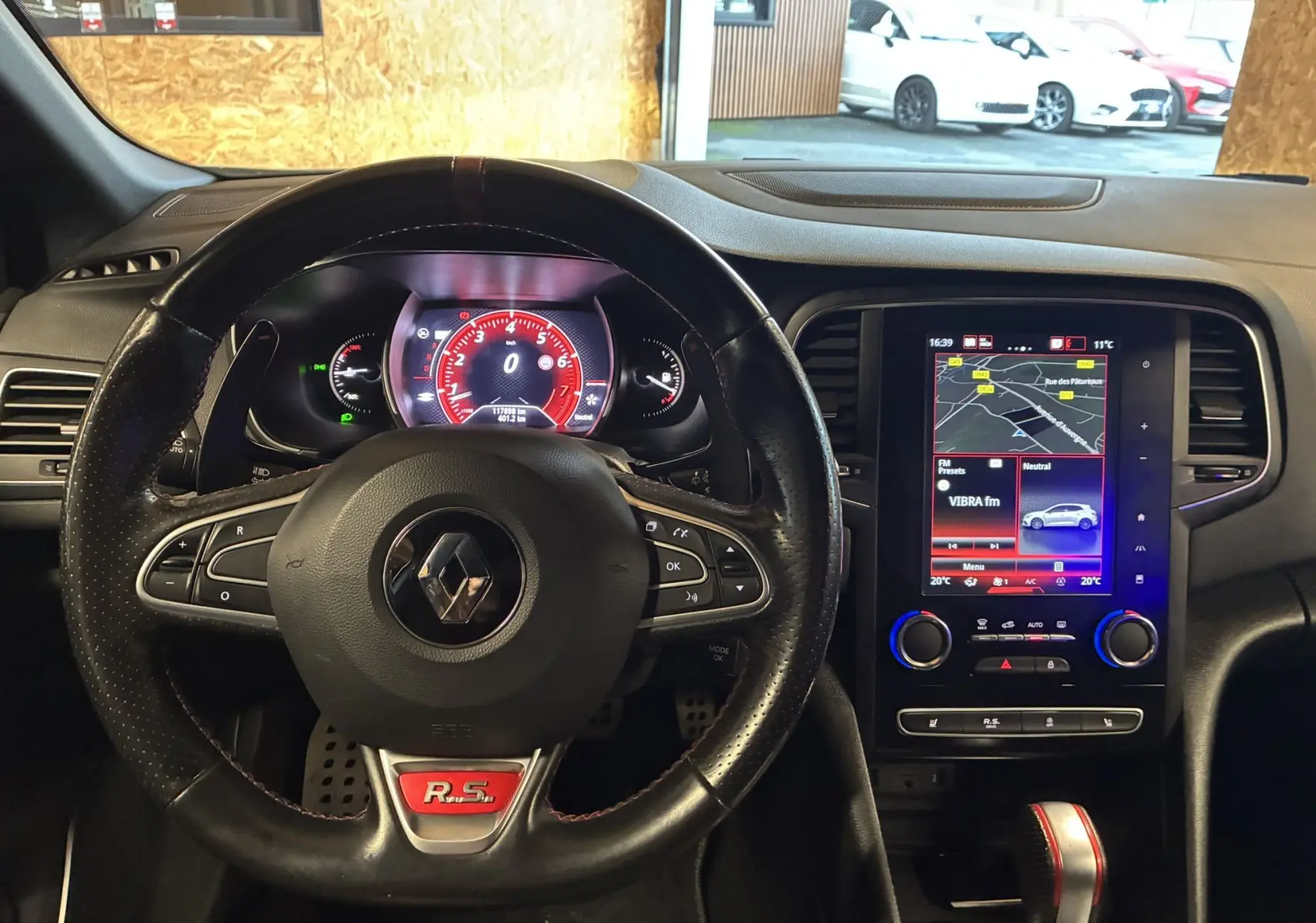 Gros plan sur la commande de lève-vitre côté gauche avec finition carbone et surpiqûres rouges dans une Renault Mégane IV RS 280 blanche.