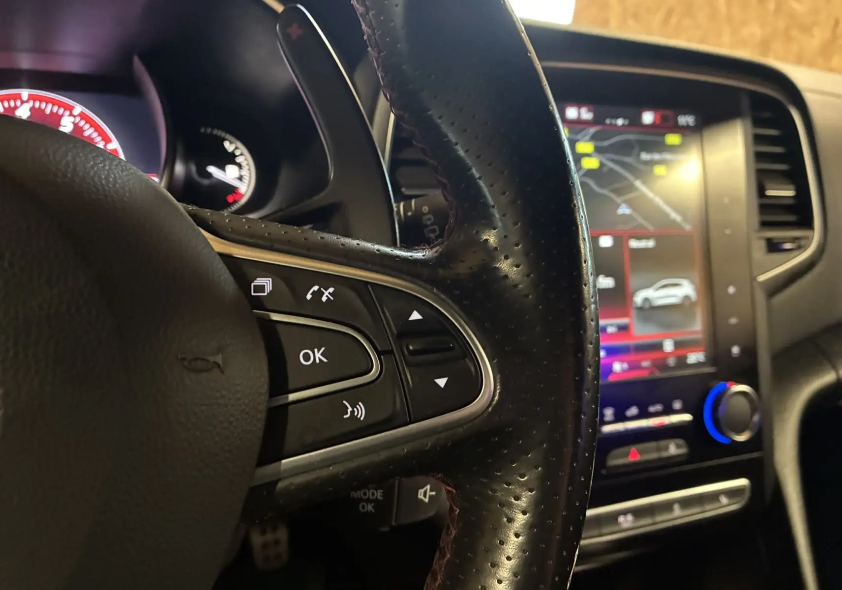 Vue intérieure côté conducteur de la Renault Mégane IV RS 280 EDC6 avec tableau de bord noir et écran tactile central allumé.