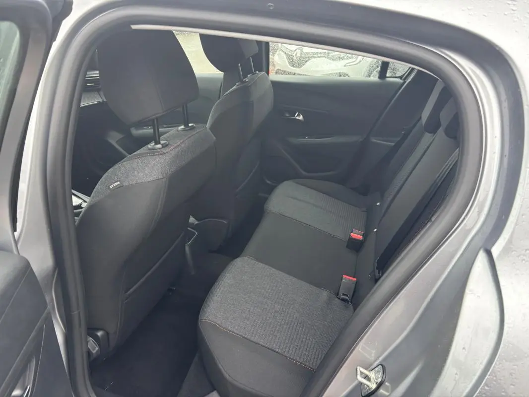 Vue intérieure côté arrière droit du Peugeot 208 gris 2025, montrant les sièges arrière en tissu bicolore.