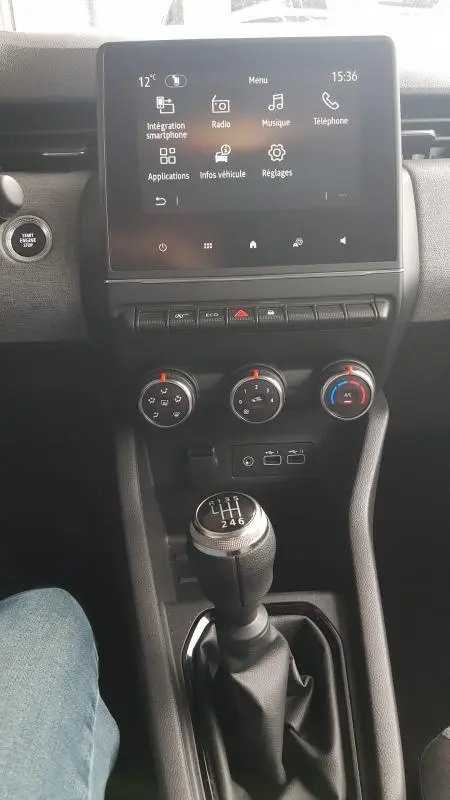 Vue intérieure centrée sur la console centrale de la Renault Clio gris 2025, avec écran tactile et levier de vitesse manuel.