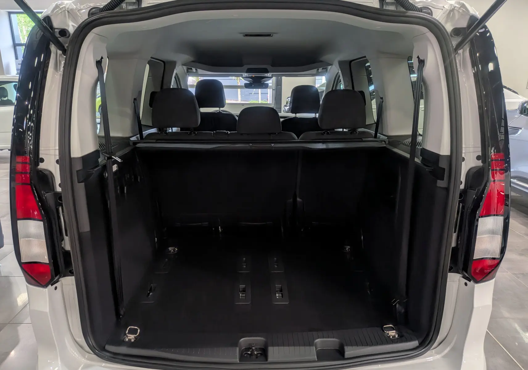 Vue arrière ouverte du Volkswagen Caddy blanc 2025 montrant l'espace de chargement et les sièges arrière noirs.