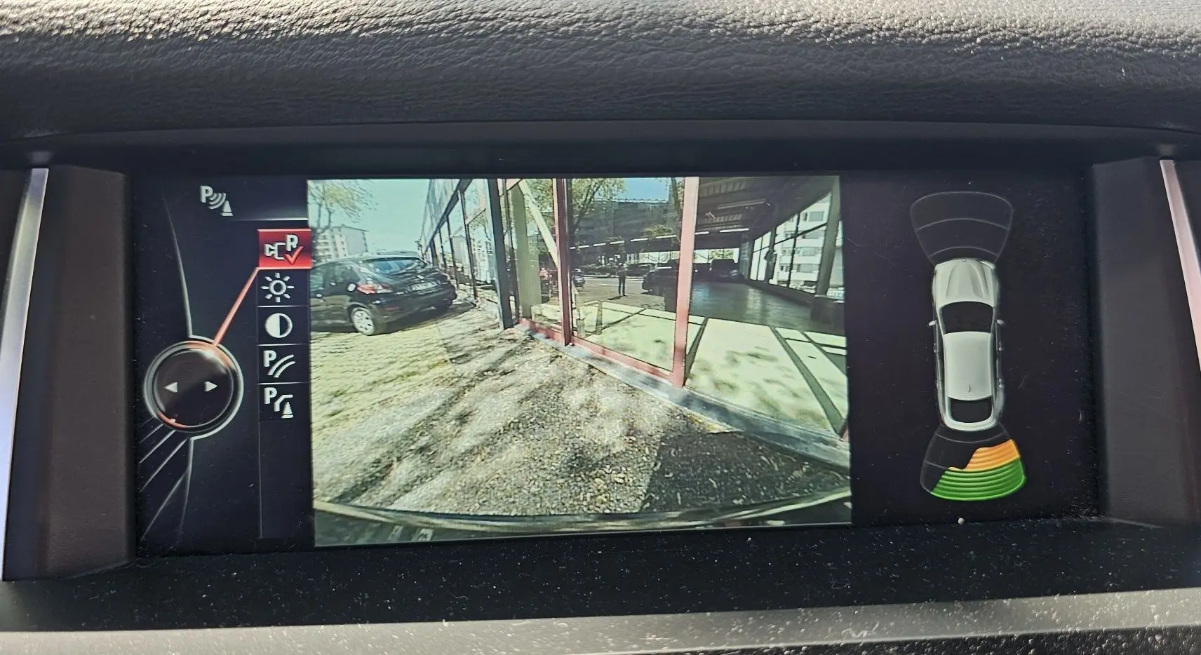 Écran de caméra de recul d'une BMW X4 xDrive20d noire, affichant l'arrière et les capteurs de stationnement actifs.