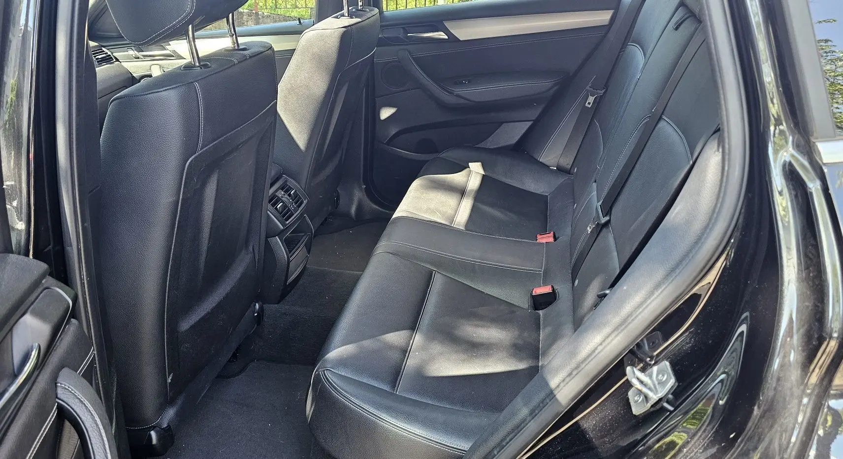 Vue intérieure côté gauche sur les sièges arrière en cuir noir du BMW X4 xDrive20dA 2015 finition M Sport.