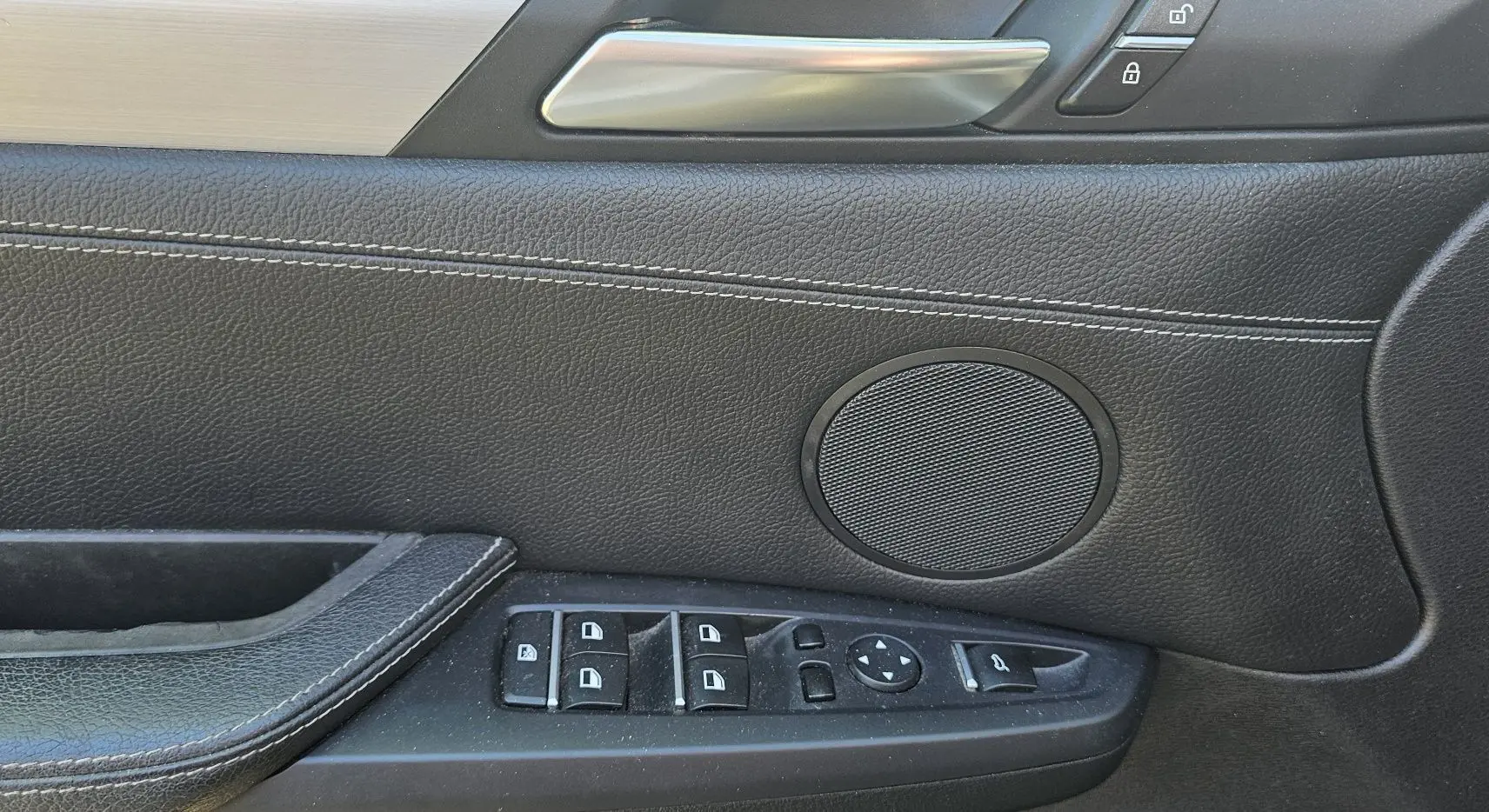 Détail de la porte côté conducteur du BMW X4 xDrive20dA 2015 noir, avec commandes de vitres et haut-parleur intégré.