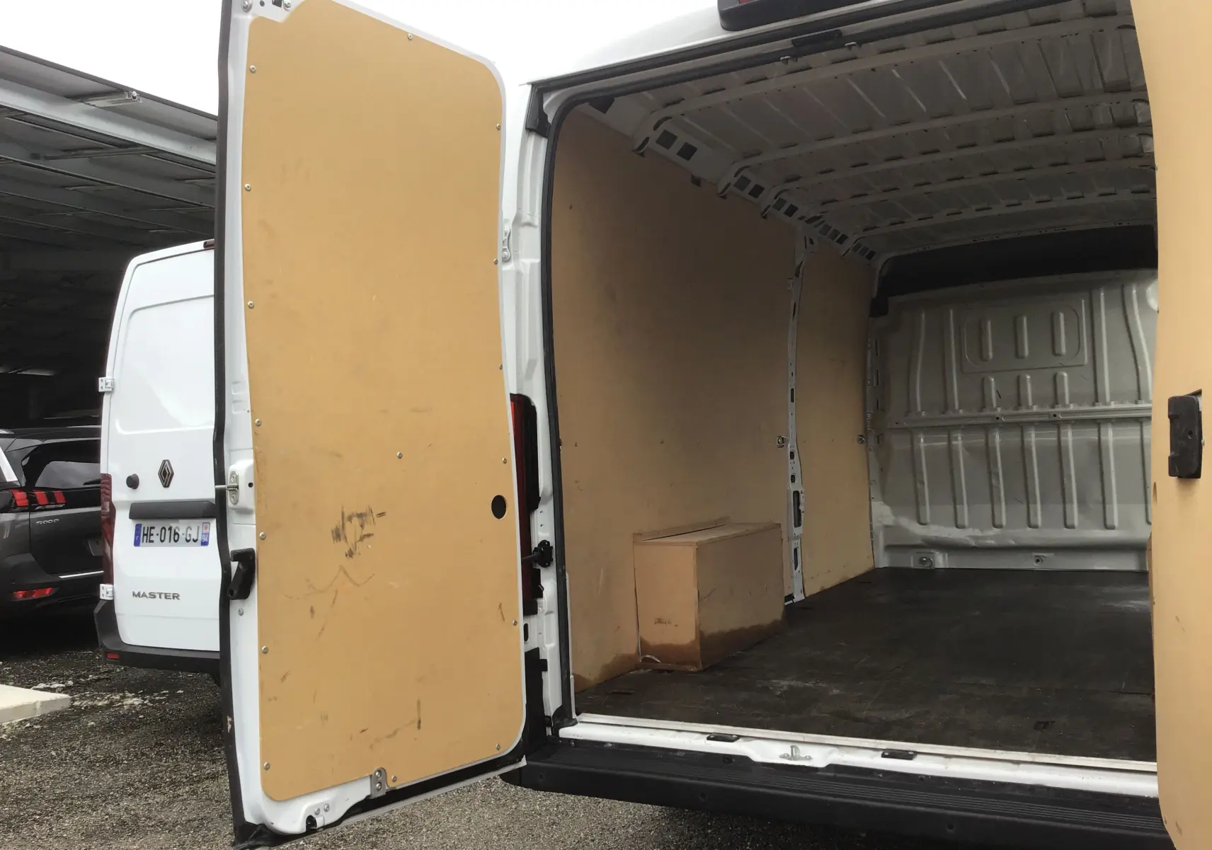 Vue arrière du FIAT Ducato Fourgon blanc 2024 avec portes ouvertes montrant l'intérieur vide et protégé par des panneaux bois.