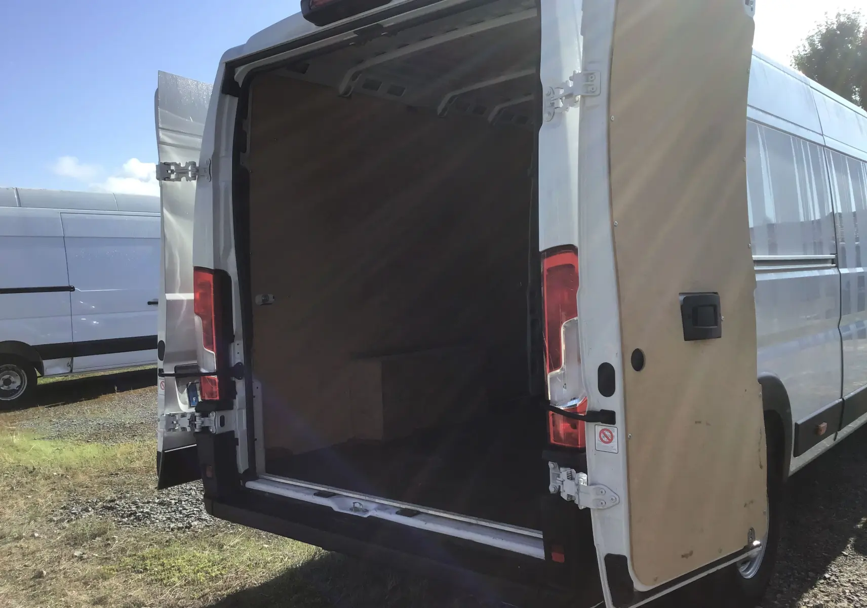 Vue arrière d’un FIAT Ducato Fourgon blanc 2024 avec portes arrière ouvertes montrant l’espace de chargement vide.