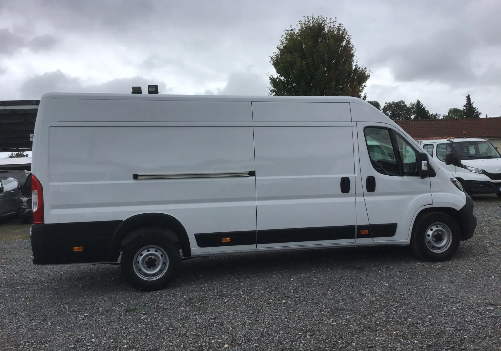 Vue de profil côté gauche d'un FIAT Ducato Fourgon blanc XLH2 3T5 avec porte coulissante et jantes acier.