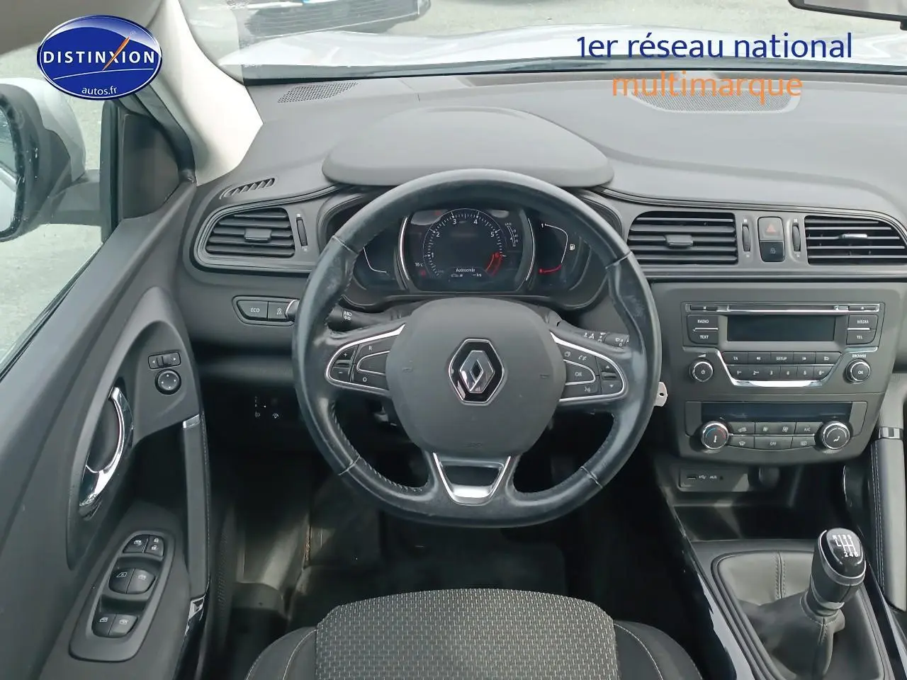 Vue intérieure centrée sur le volant cuir multifonction et la console centrale du Renault Kadjar gris 2017.