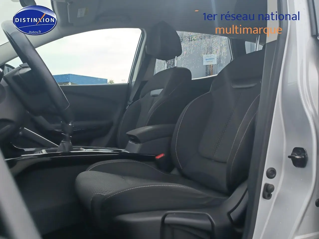 Intérieur vue côté gauche montrant les sièges avant noirs et l'accoudoir central du Renault Kadjar gris 2017.