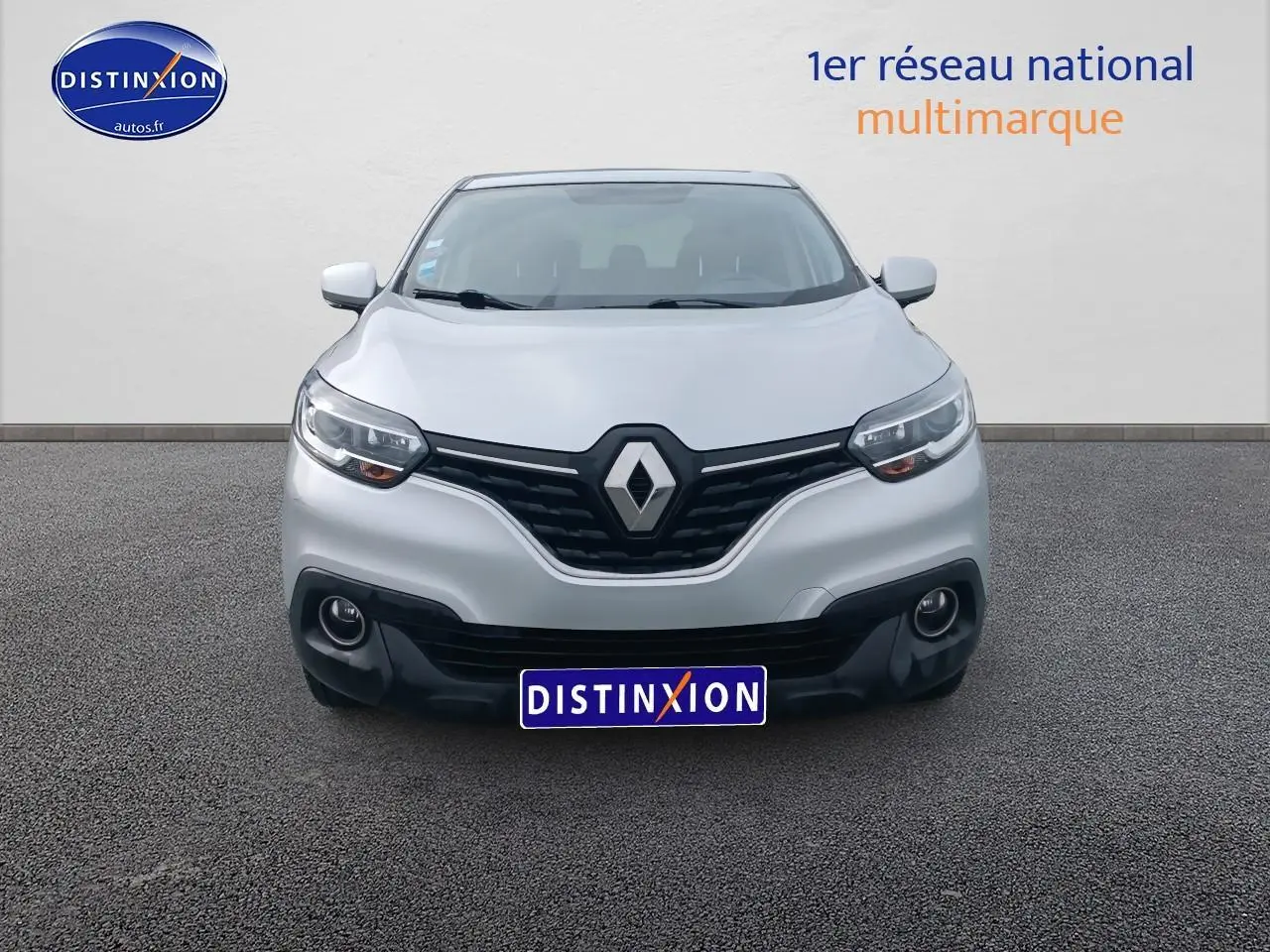 Vue frontale d'un Renault Kadjar gris avec calandre noire et phares allumés sur fond neutre.