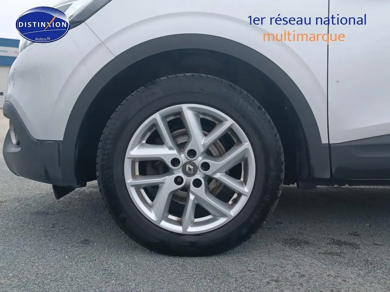 Gros plan sur la roue avant gauche en jante alu du Renault Kadjar gris, avec partie basse de la carrosserie visible.