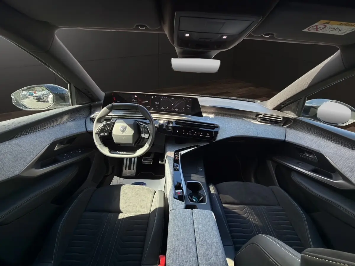Vue intérieure avant du Peugeot 5008 2025 avec finition Alcantara gris clair et tableau de bord numérique large.