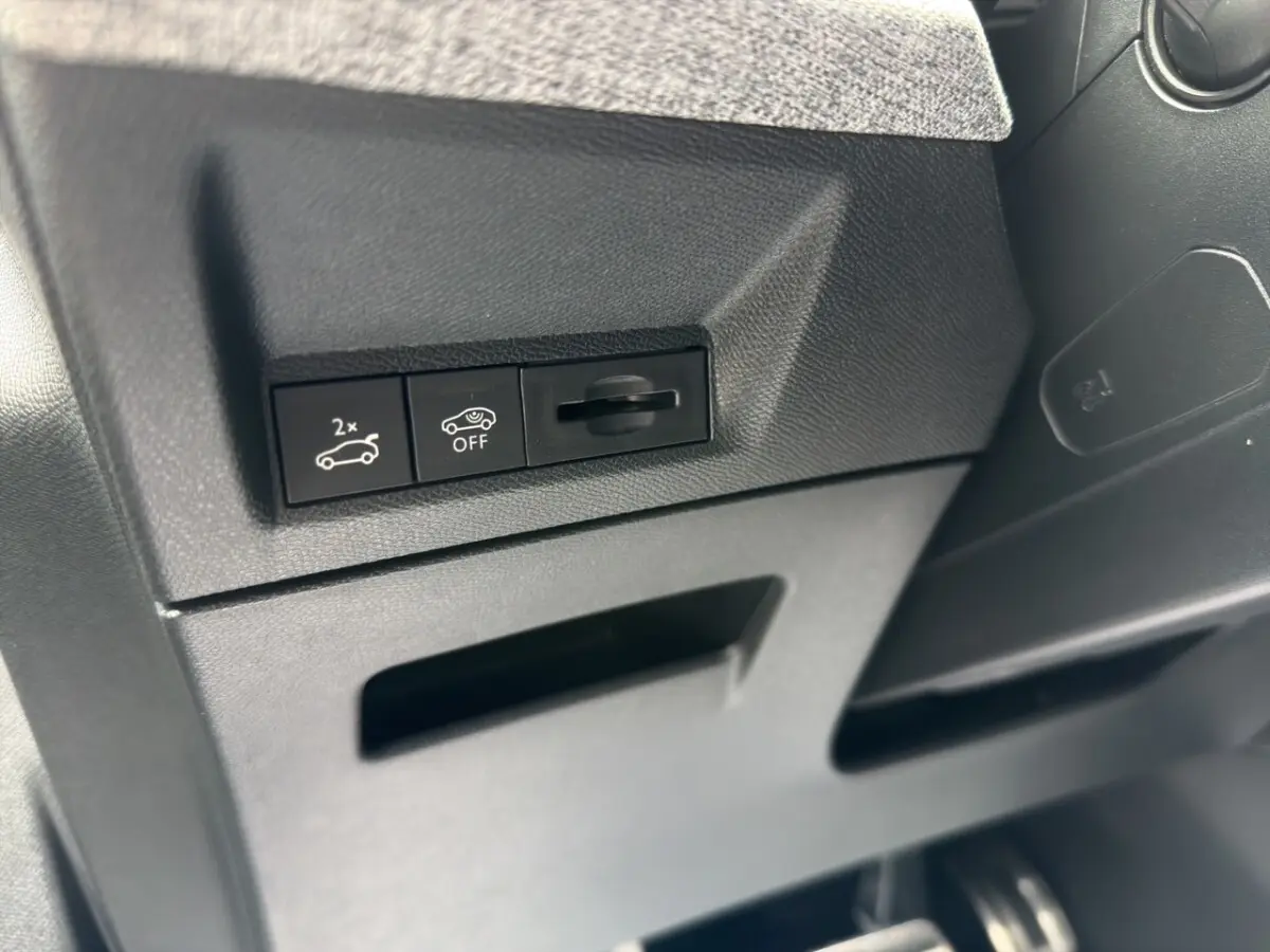 Gros plan sur les commandes de coffre et désactivation du système, intérieur noir du Peugeot 5008 hybride 2025.