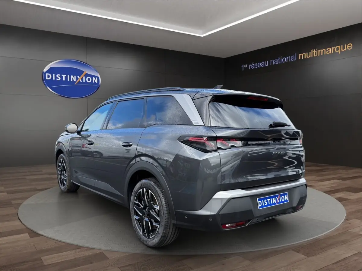 Peugeot 5008 gris foncé vue 3/4 arrière droit, avec jantes noires et toit noir brillant en showroom.
