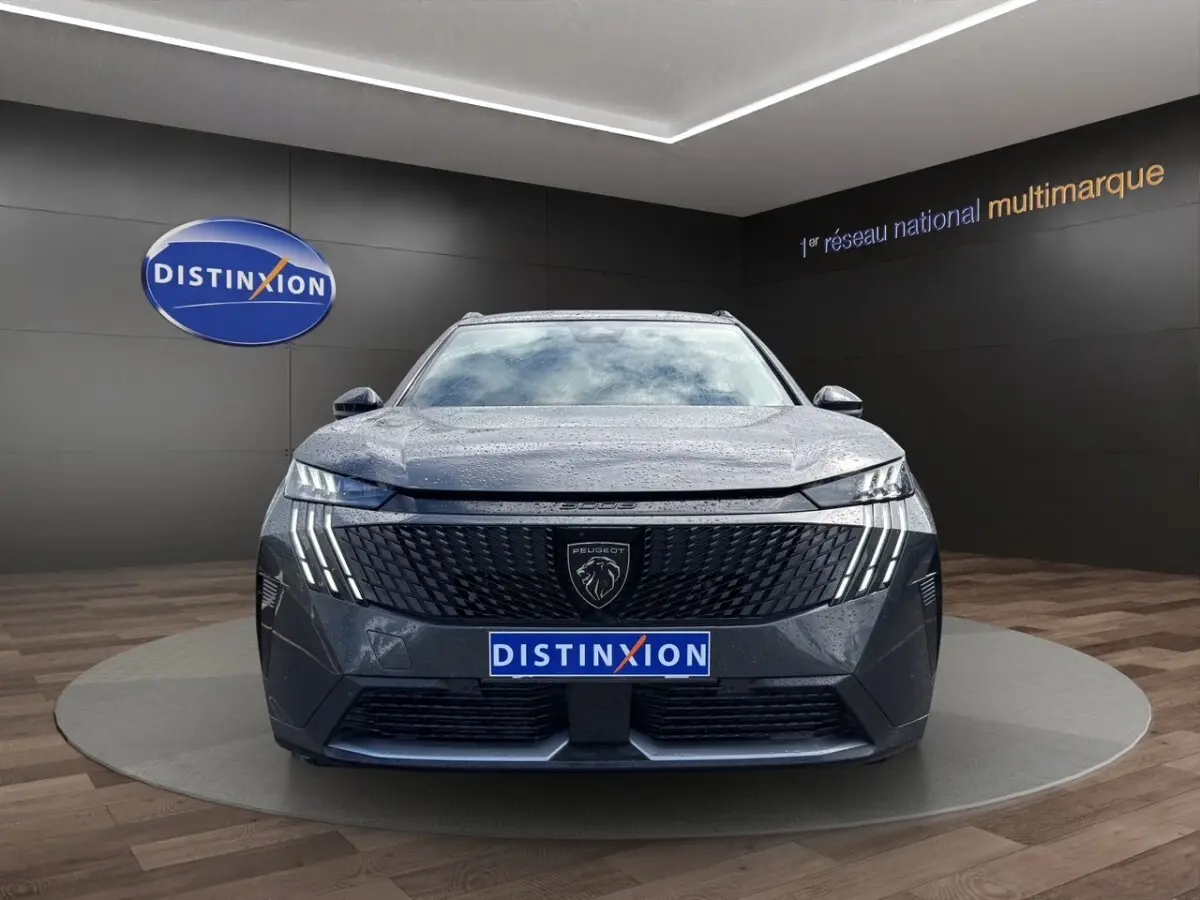 Peugeot 5008 gris foncé vue de face, avec calandre noire et feux LED verticaux allumés.