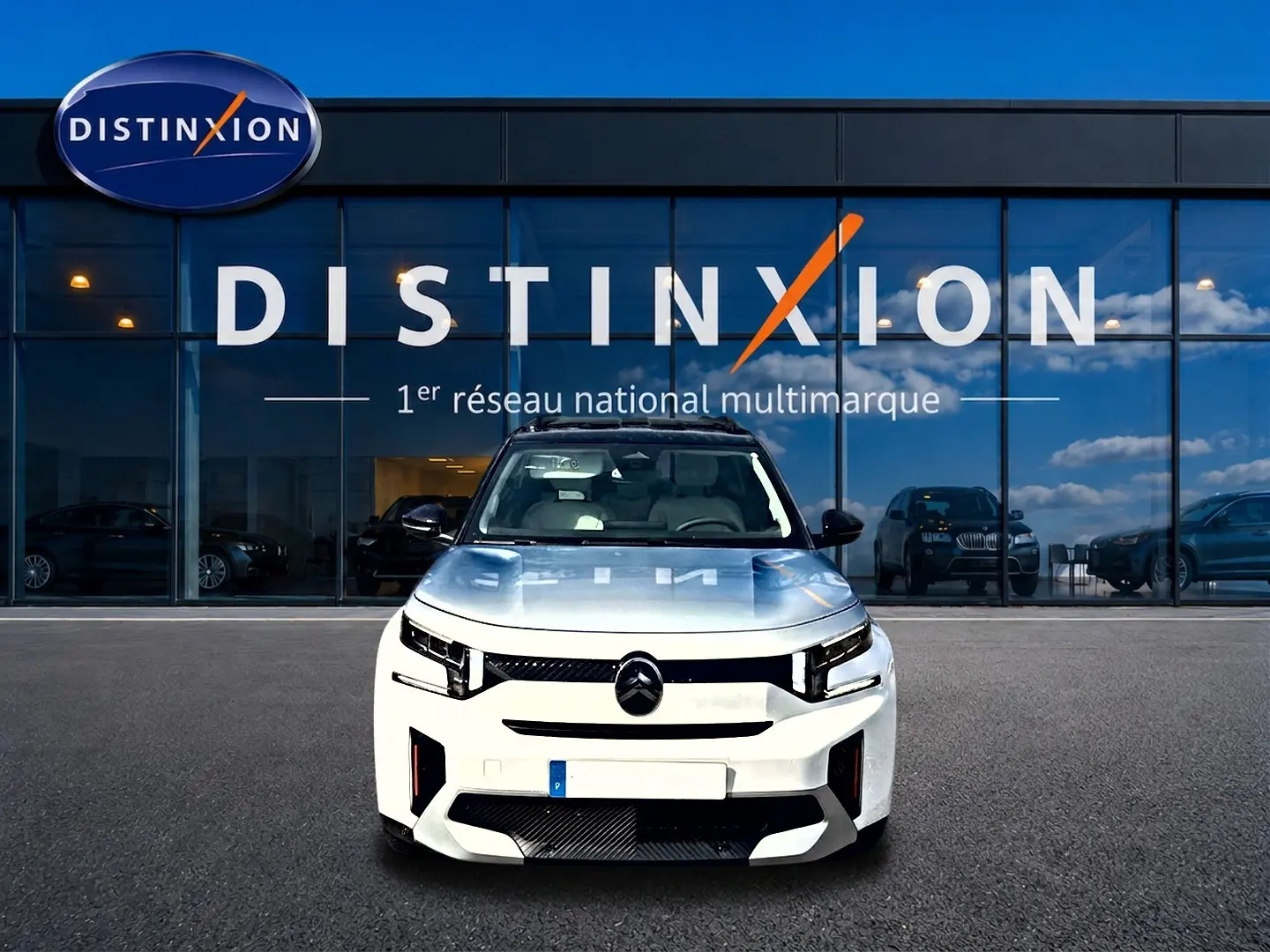 Vue frontale d'un Citroën C3 Aircross blanc 2026 avec calandre noire et phares LED, devant une vitrine Distinxion.