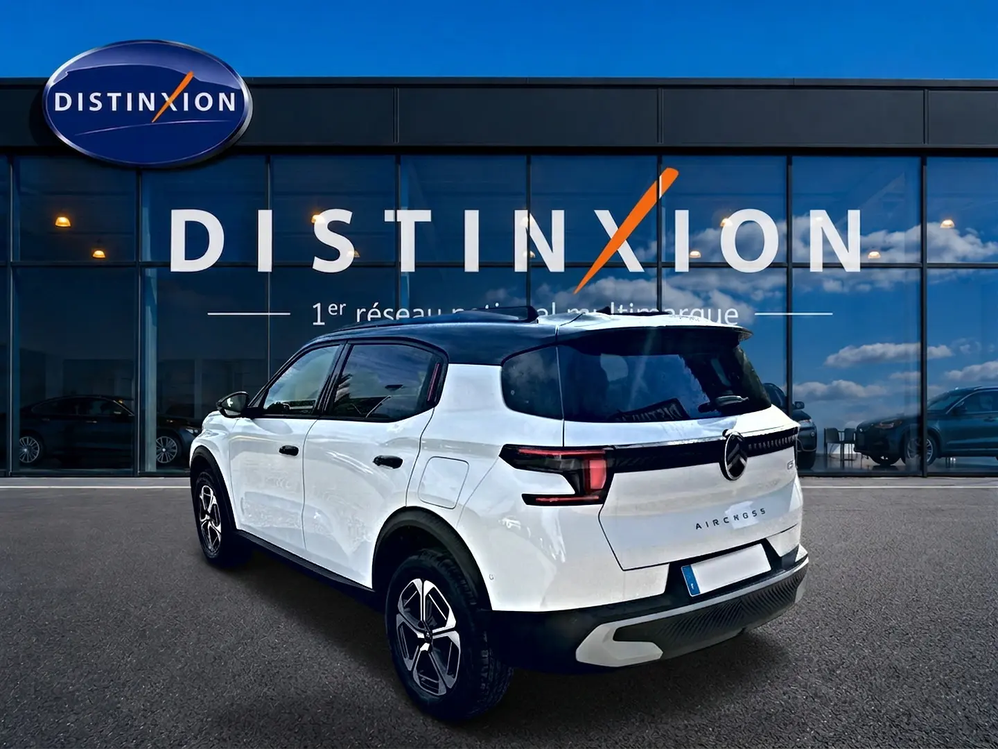 Vue 3/4 arrière droite d'un Citroën C3 Aircross blanc avec toit noir et feux arrière LED, devant une vitrine Distinxion.