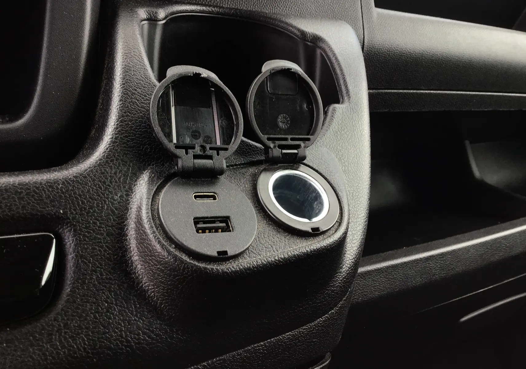 Prise USB-C et USB-A avec allume-cigare dans l'habitacle noir du Fiat Ducato Fourgon XLH2 2024.