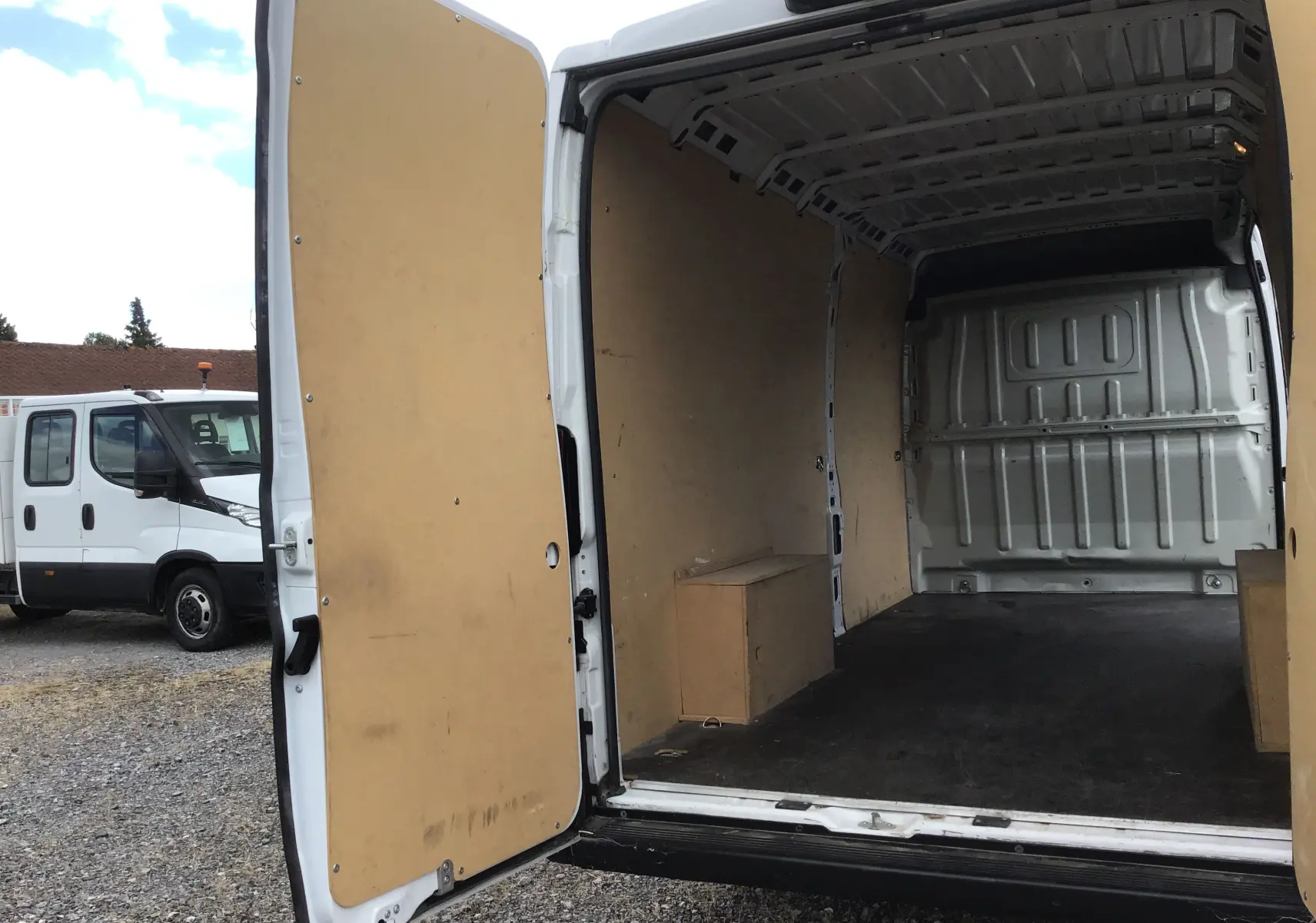 Vue arrière ouverte d'un FIAT Ducato Fourgon blanc 2024, montrant l'intérieur vide avec habillage bois clair.