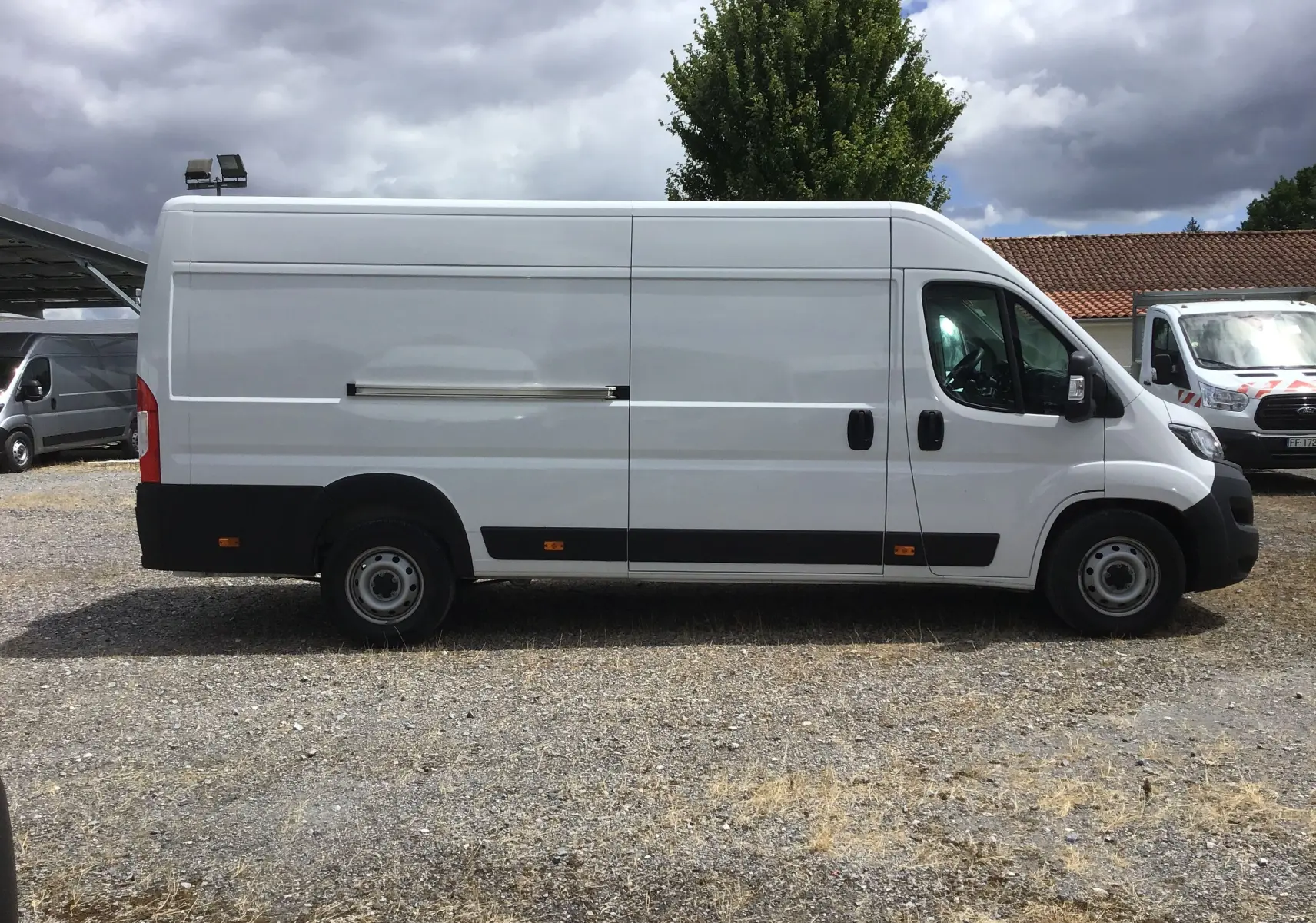 Fourgon blanc FIAT Ducato XLH2 3T5 vu de profil côté droit, avec porte coulissante et jantes acier simples.