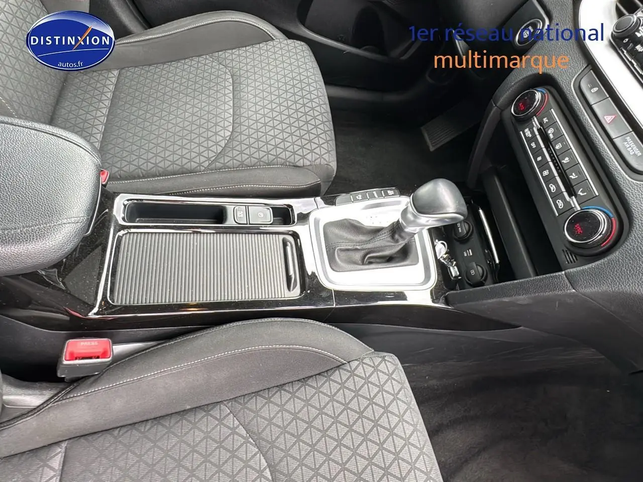 Vue intérieure centrée sur la console centrale et les sièges tissu noir de la Kia CEE'D SW 2020 avec boîte automatique.