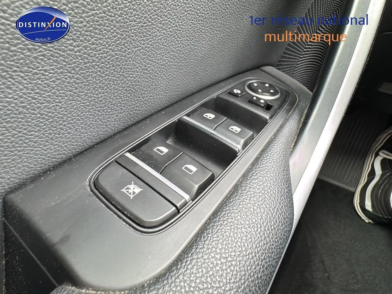 Gros plan sur les commandes des vitres électriques côté conducteur d'une Kia CEE'D SW noire de 2020.