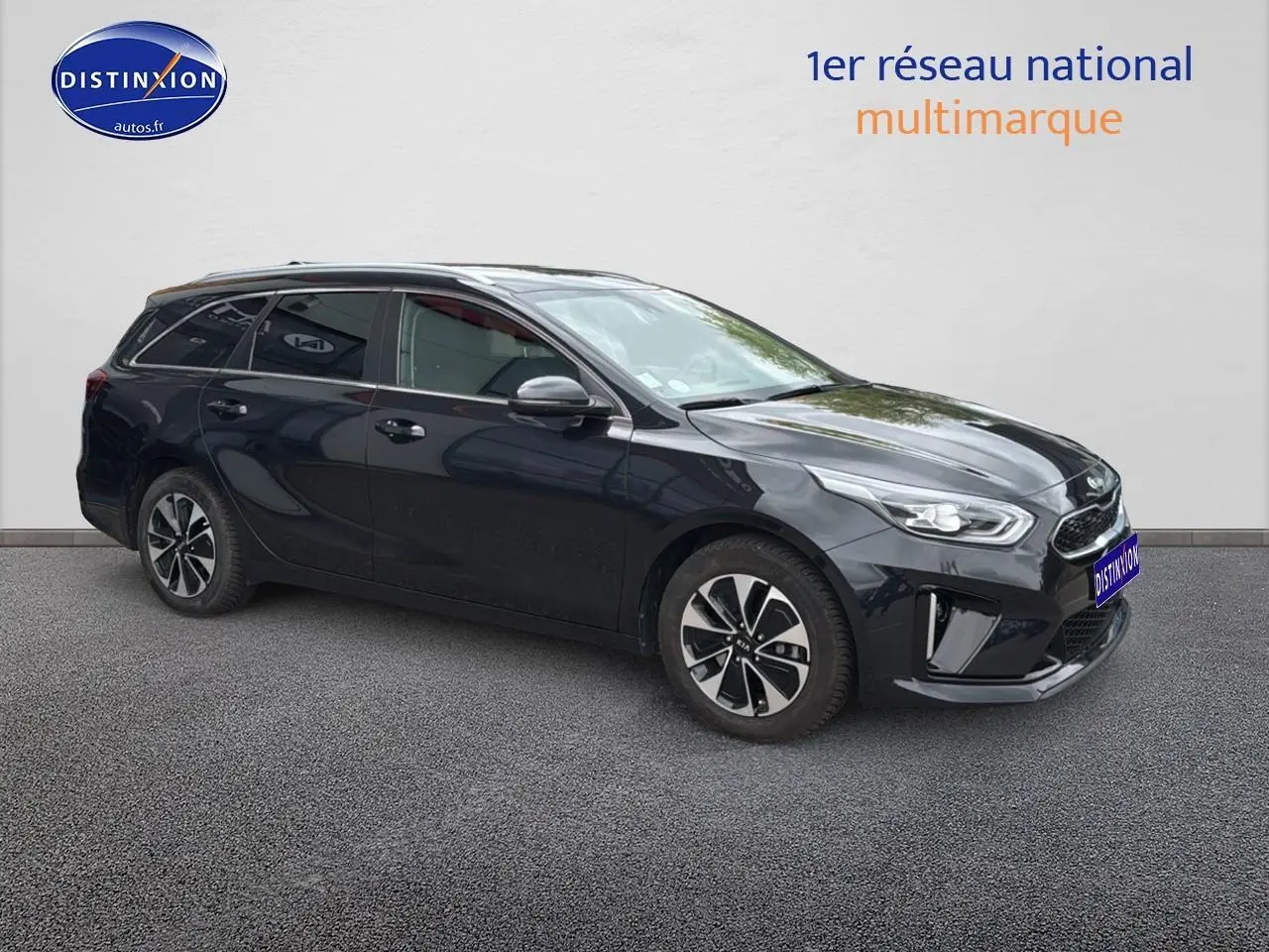 KIA CEE'D SW noir en 3/4 avant droit, avec jantes alu et barres de toit visibles sur fond neutre.