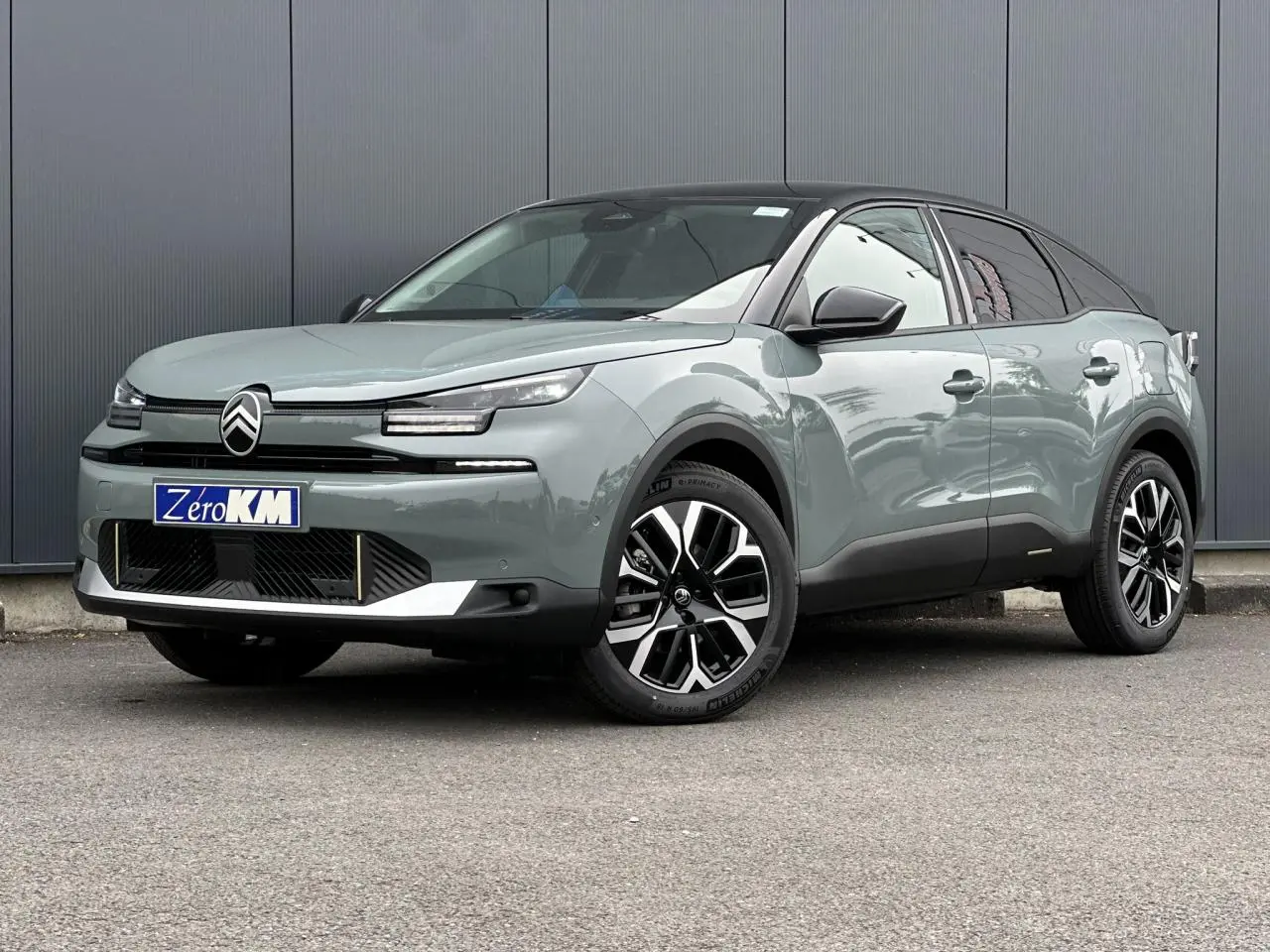 Citroën C4 2025 Manhattan Green vue 3/4 avant avec toit noir et jantes alliage 18 pouces diamantées.