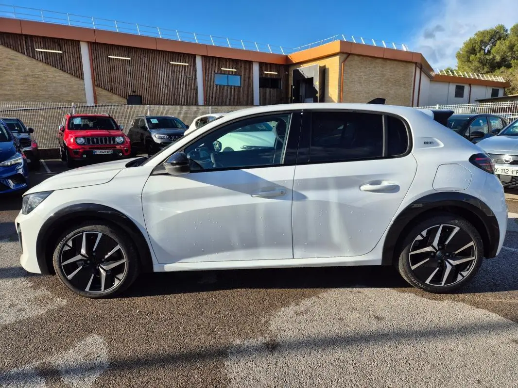 Profil droit d'une Peugeot 208 Hybrid 136 e-DCS6 GT blanche avec jantes alliage 17 pouces et vitres teintées.