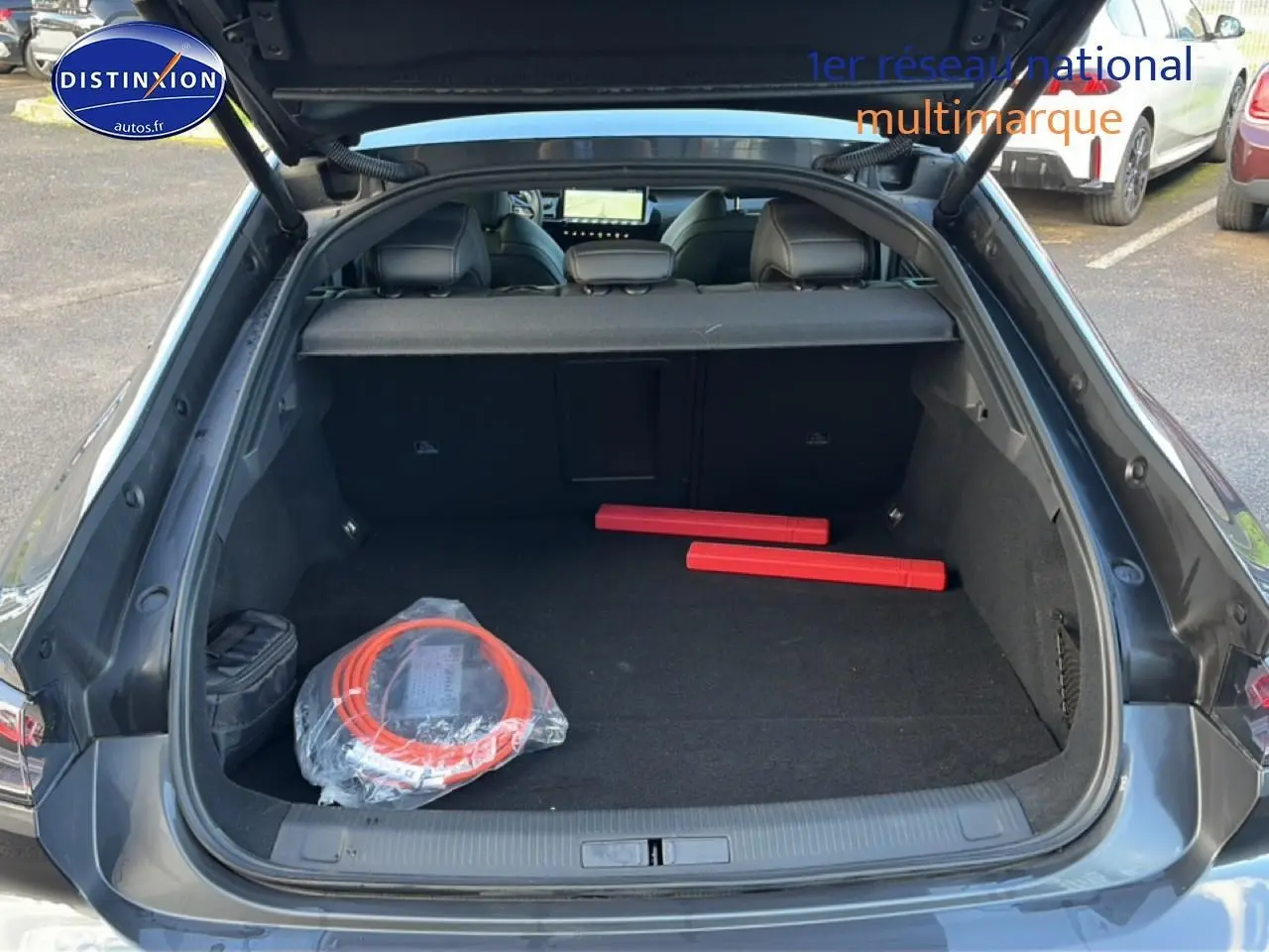 Coffre ouvert vu de l'arrière d'une Peugeot 508 Hybrid 225 GT gris titane avec accessoires de sécurité à l'intérieur.
