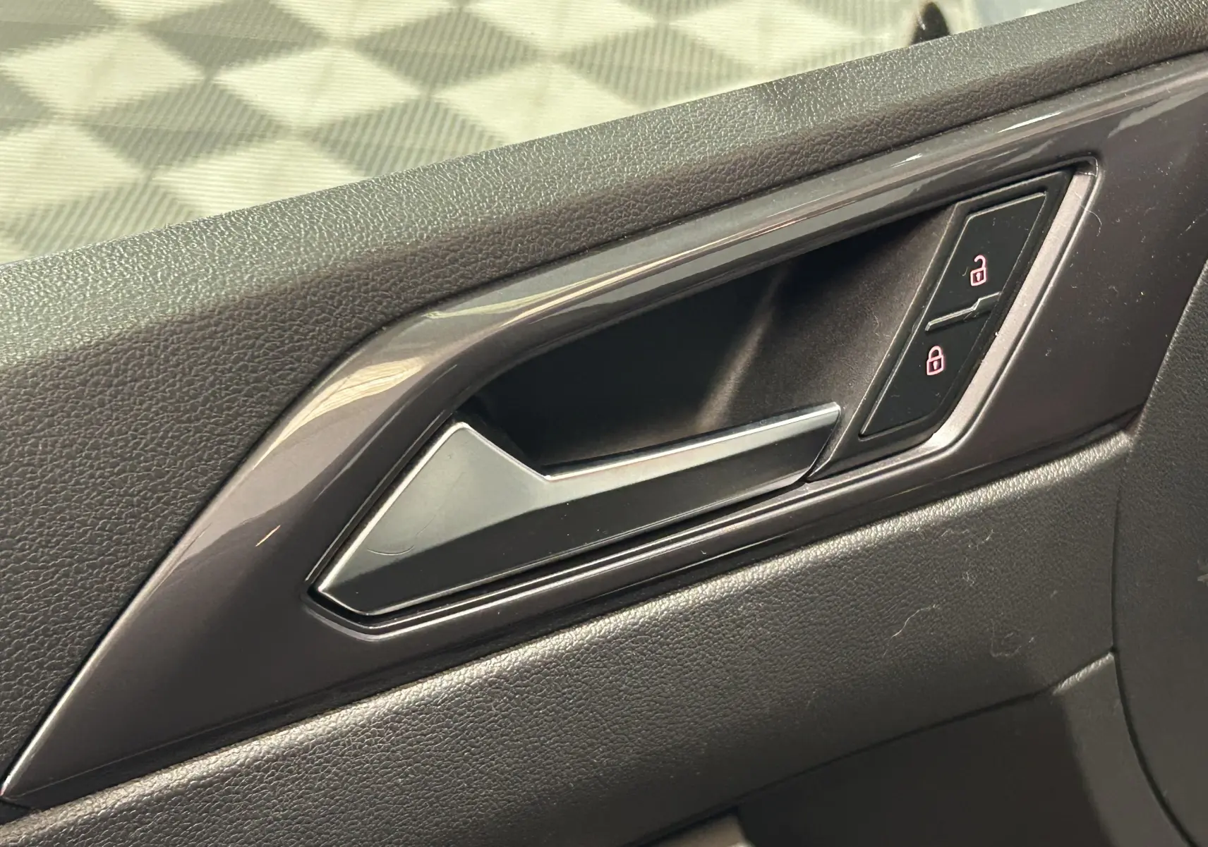 Poignée intérieure de porte côté droit de Volkswagen Polo gris, avec commandes de verrouillage centralisé.