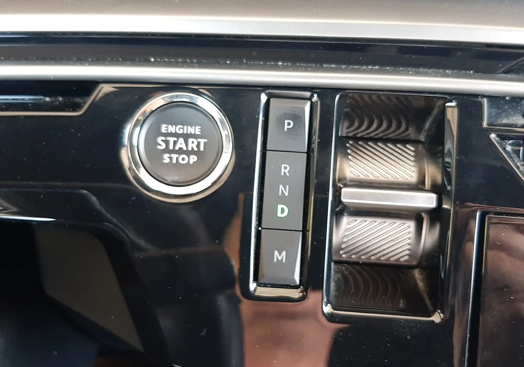 Détail de la console centrale du Peugeot 5008 Hybrid 2025 montrant le bouton start/stop et la sélection de boîte auto sur fond noir brillant.