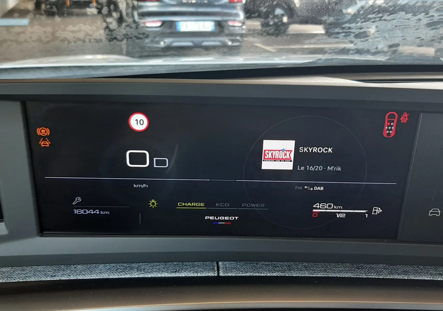 Vue intérieure du tableau de bord numérique du Peugeot 5008 Hybrid 2025, affichant la radio et l'autonomie restante.