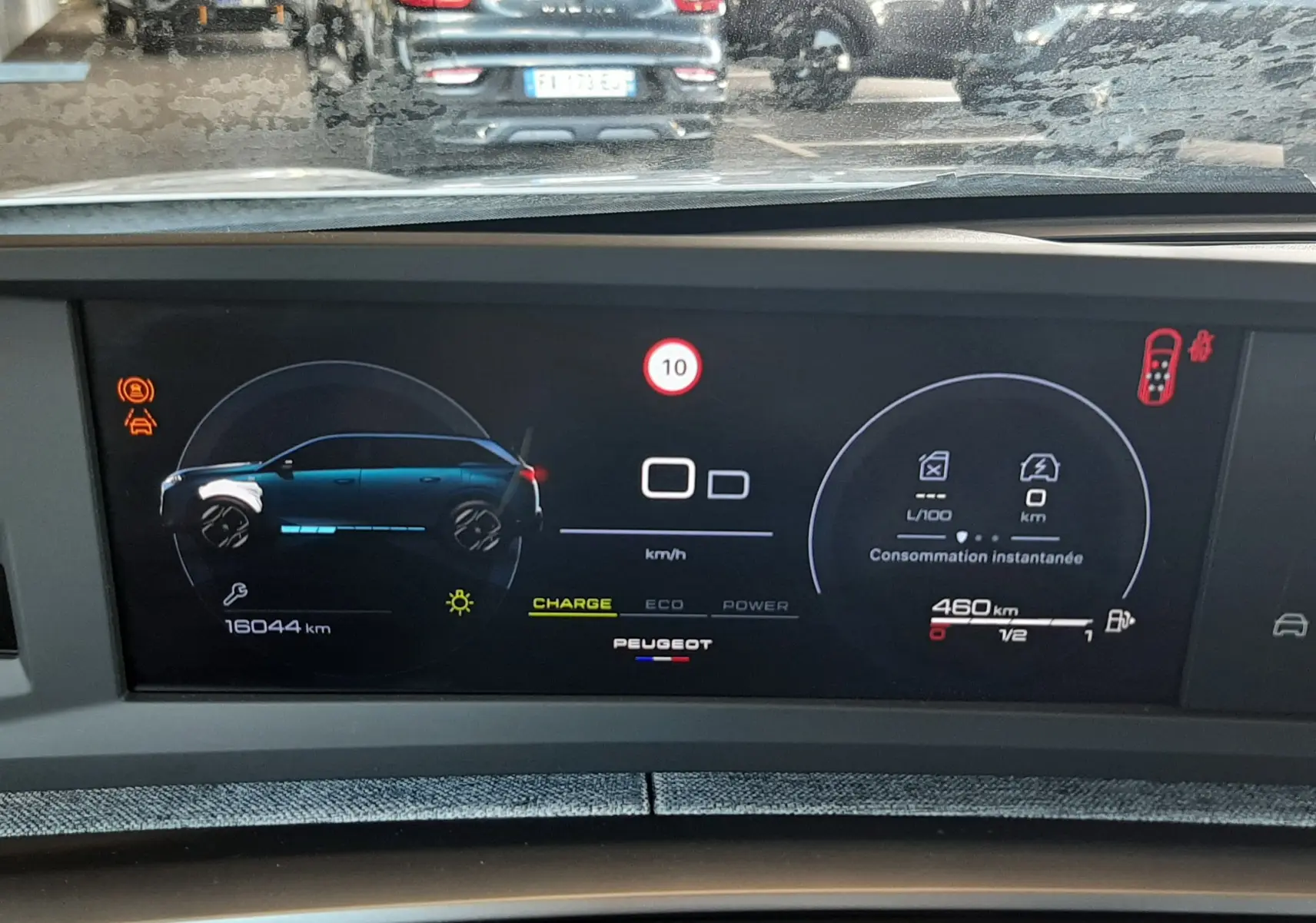 Tableau de bord numérique du Peugeot 5008 Hybrid blanc, affichant consommation et autonomie, vue intérieure frontale.