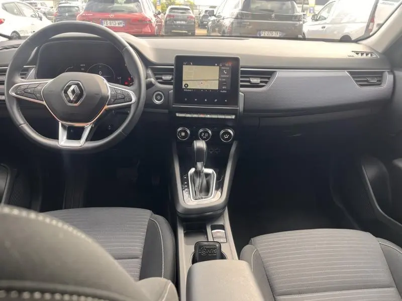 Vue intérieure avant du Renault Arkana blanc perle 2023, tableau de bord avec écran tactile et volant multifonction cuir.