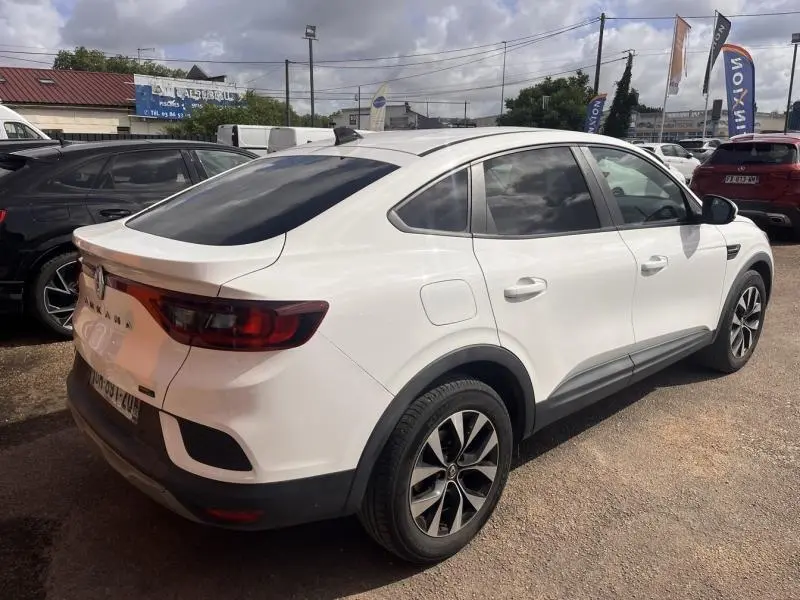 Vue 3/4 arrière droite d'un Renault Arkana blanc perle avec vitres teintées et jantes alliage noires.