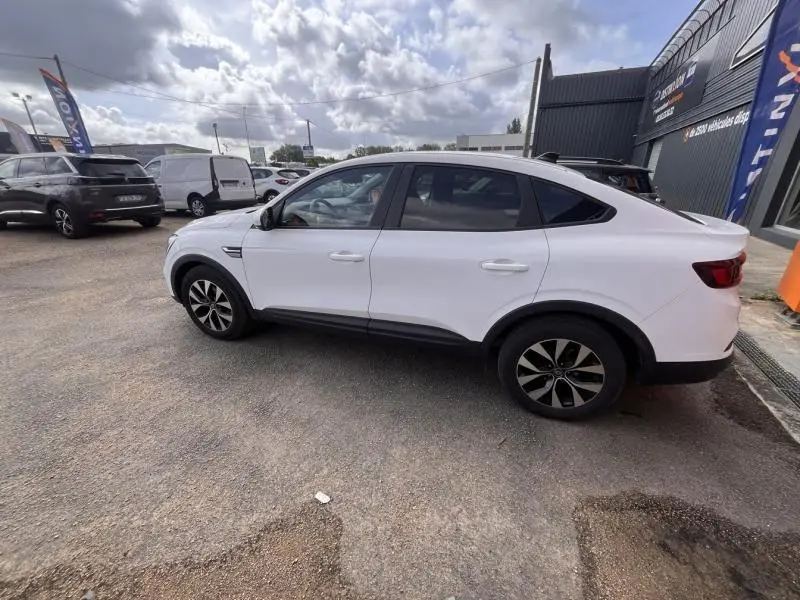 Renault Arkana blanc perle vu de profil côté gauche, avec jantes alu et vitres arrière surteintées.