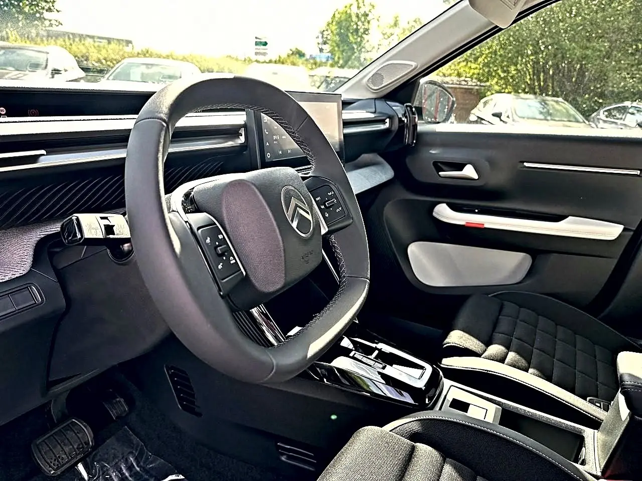 Vue intérieure côté conducteur du Citroën C3 Aircross 2026, volant multifonction et sellerie noire avec inserts gris.