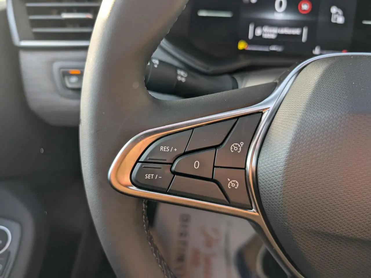 Gros plan sur les commandes du régulateur de vitesse au volant de la Renault Clio 2025 finition Techno.