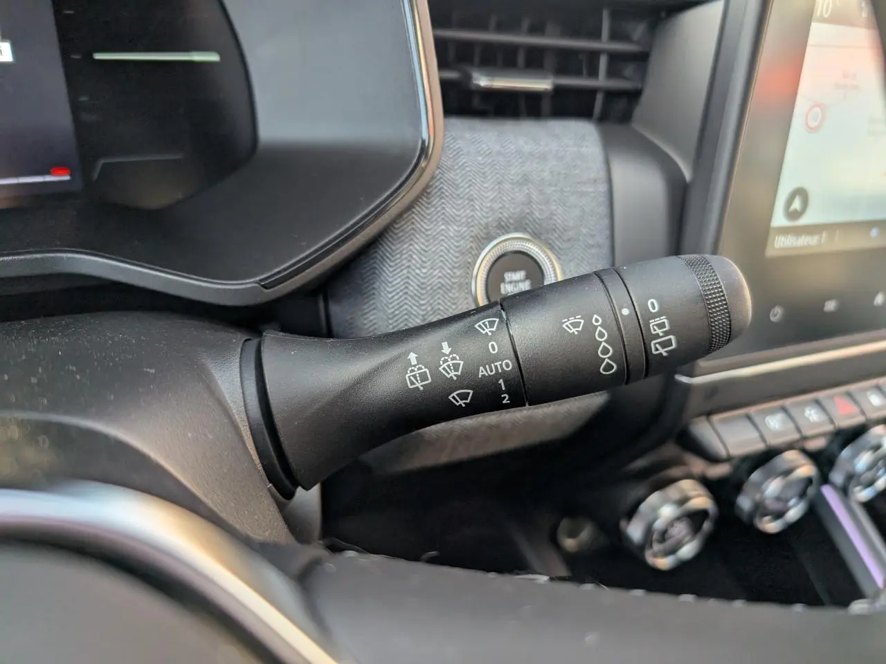 Gros plan sur la commande d'essuie-glace à gauche du volant dans l'habitacle gris mélangé de la Renault Clio 2025.