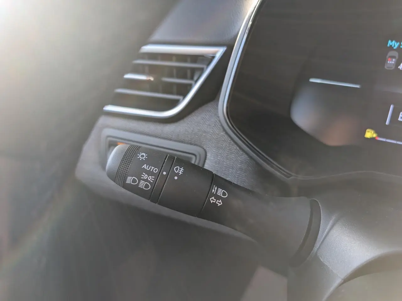 Gros plan sur la commande des feux et clignotants à gauche du volant dans une Renault Clio gris schiste 2025.