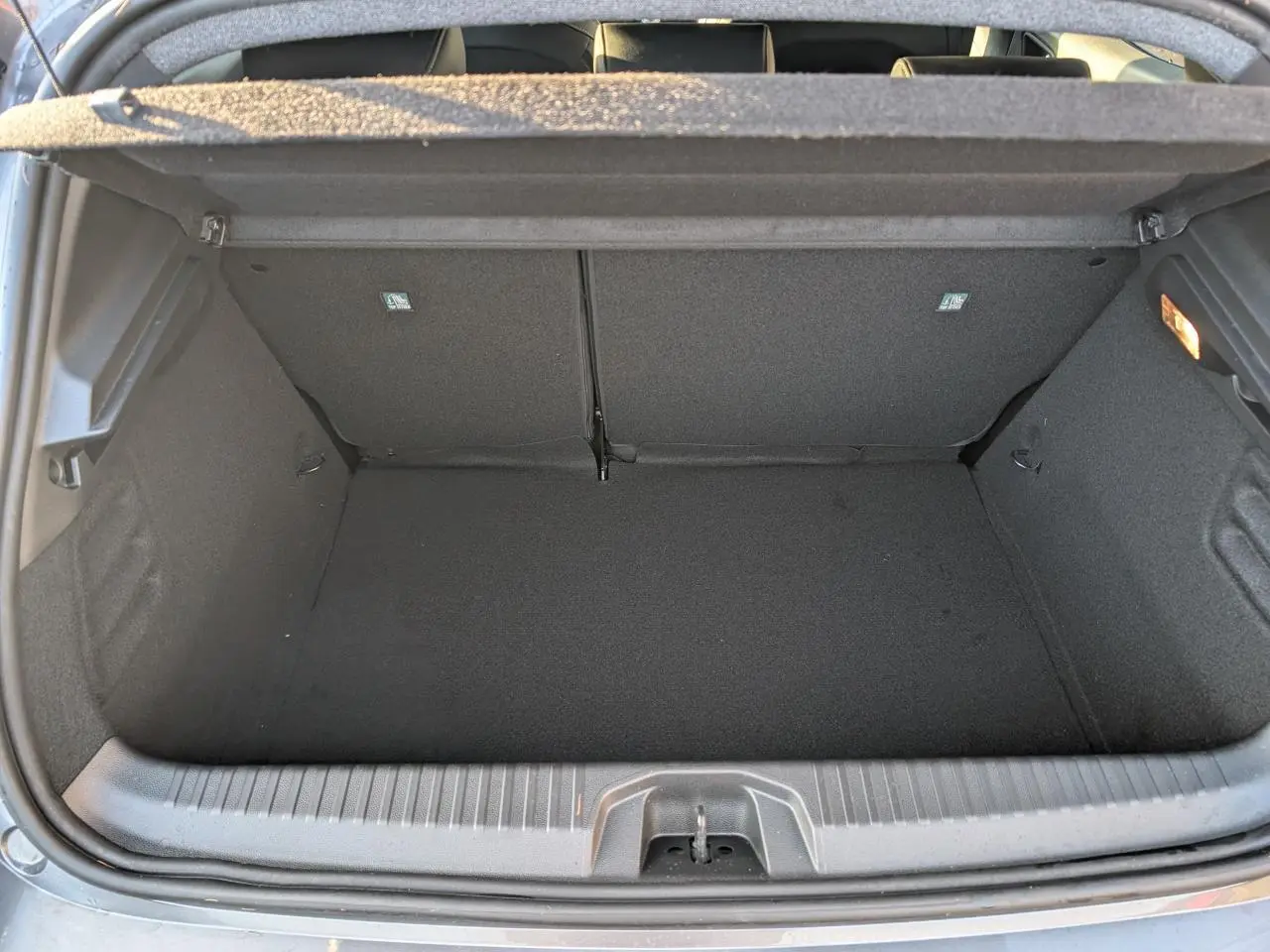 Coffre ouvert vu de l'arrière d'une Renault Clio 1.0 Tce gris schiste, espace de rangement vide et propre.